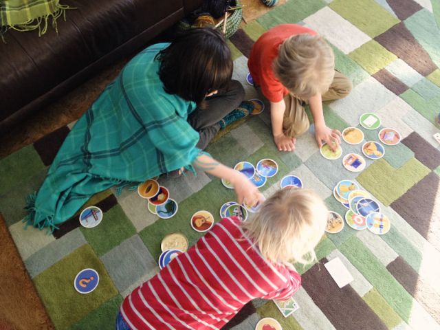 Learning Environment: Kids playing a game on a blanket, bundled in other blankets.